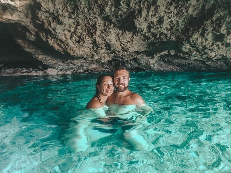 Coppia che fa il bagno nell'acqua turchese di una grotta